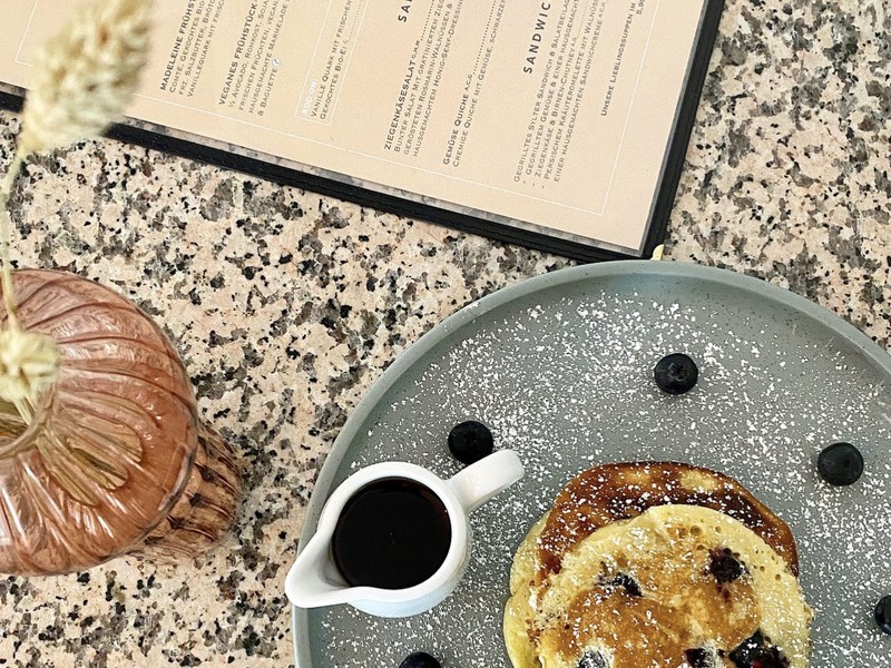 Blaubeer-Pancakes mit Ahornsirup neben der Frühstückskarte